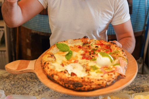 A man holding a  board with a classic Neapolitan-style pizza