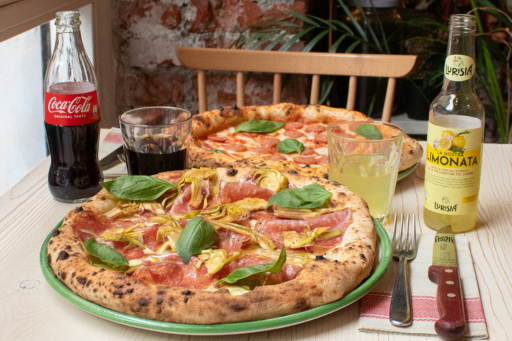 Two neapolitan-style pizzas on a table with drinks